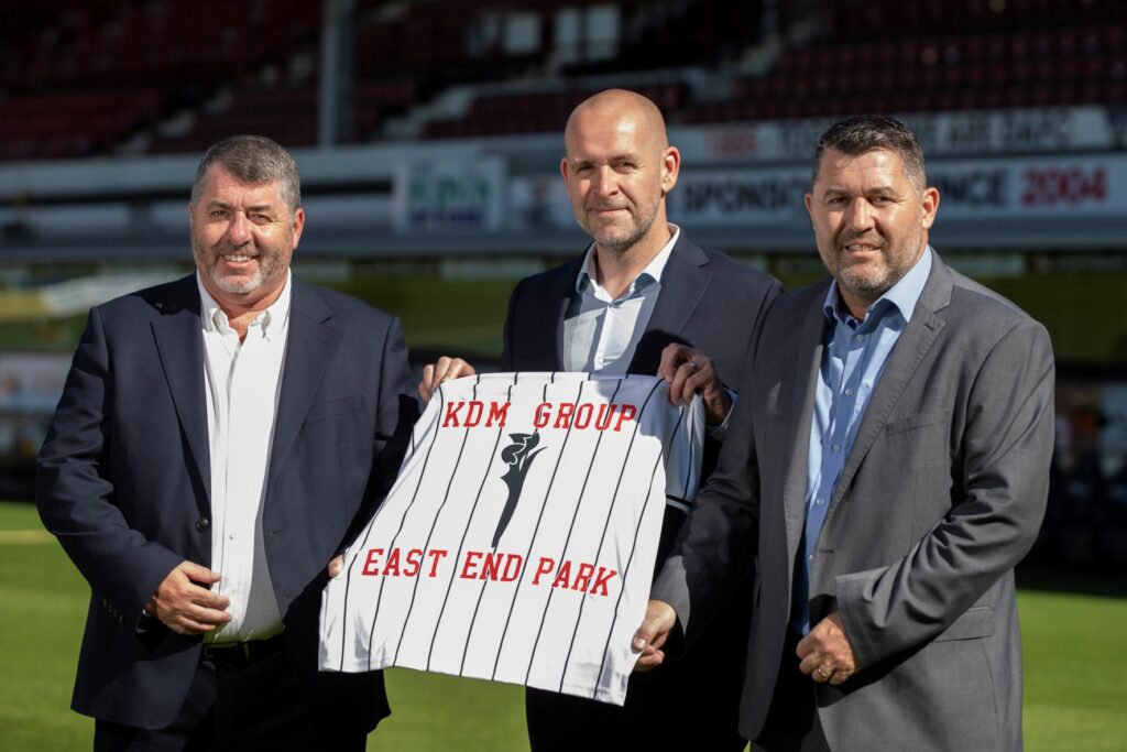 DAFC and KDM members holding a shirt reading 'KDM Group' and 'East End Park'